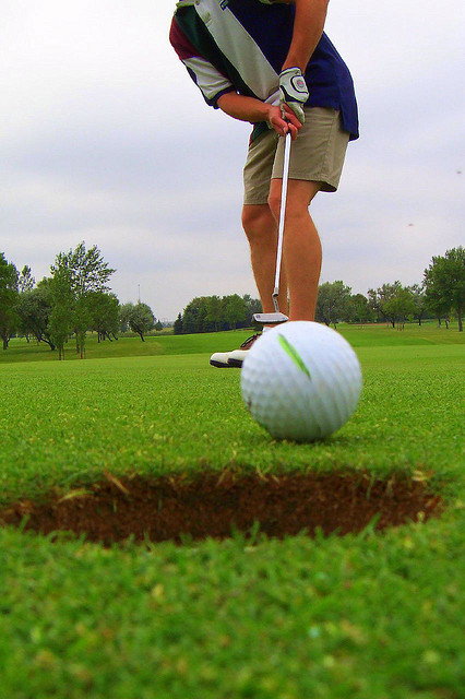Golfball rollt ins Loch.